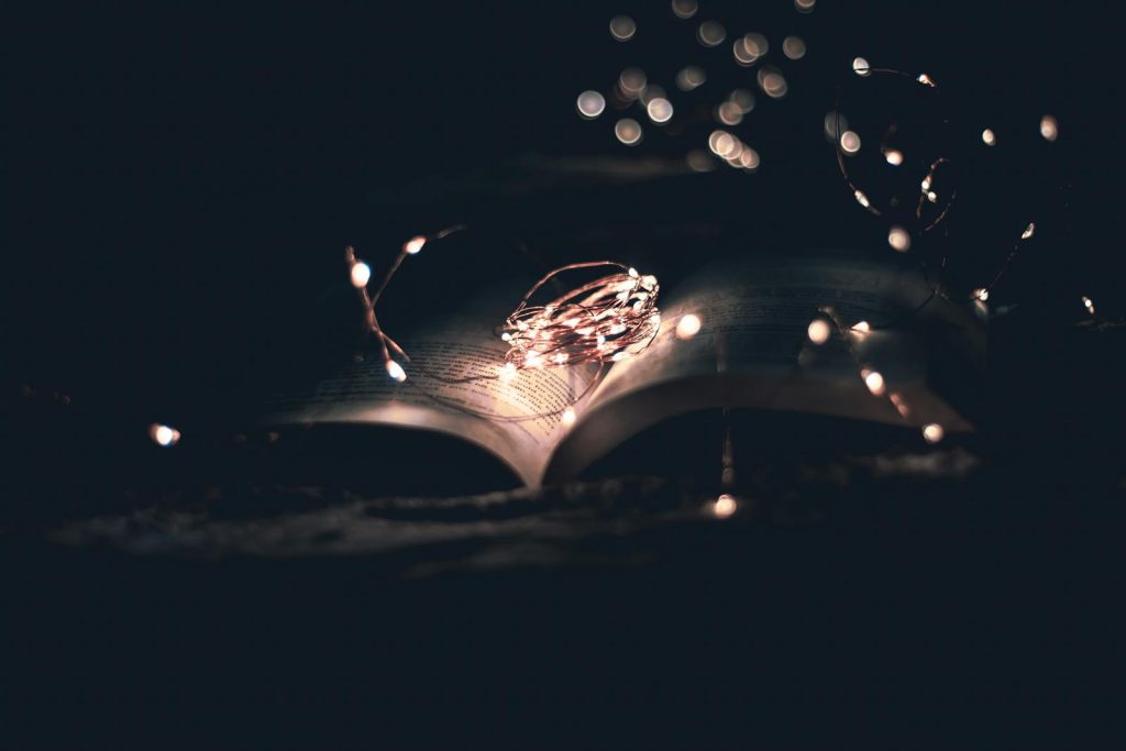 An open book beautifully illuminated by string lights, creating a magical atmosphere.