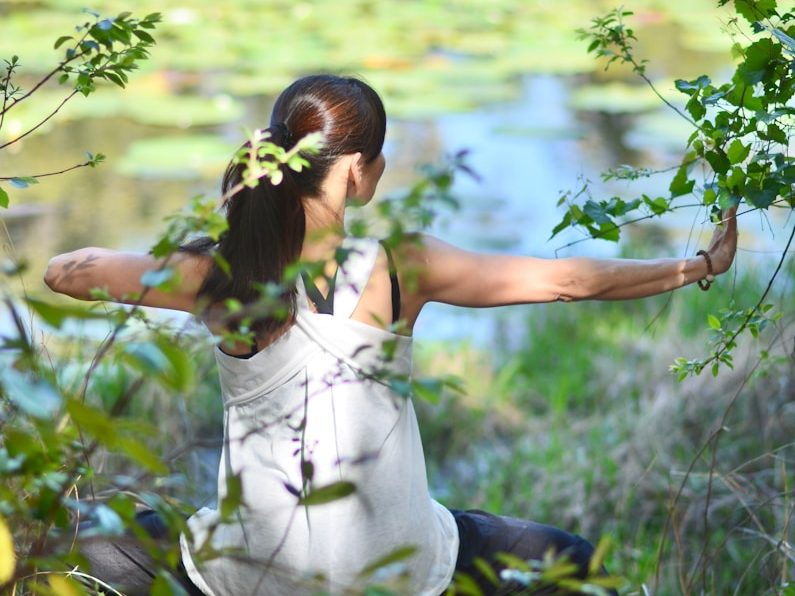 a woman in a white dress is doing yoga